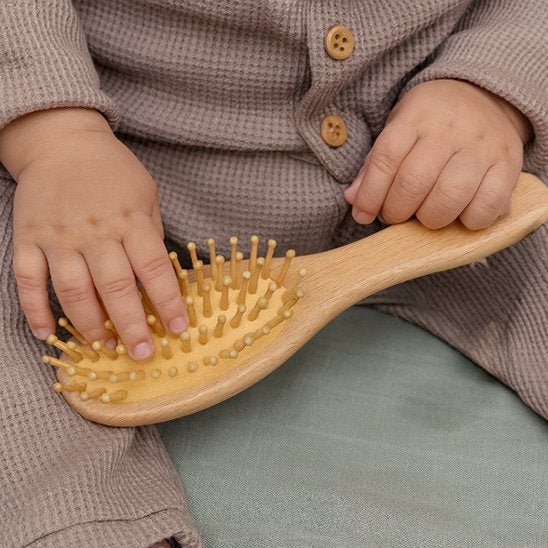 Brosse cheveux bebe bébé tenant dans ses mains sa brosse à cheveux