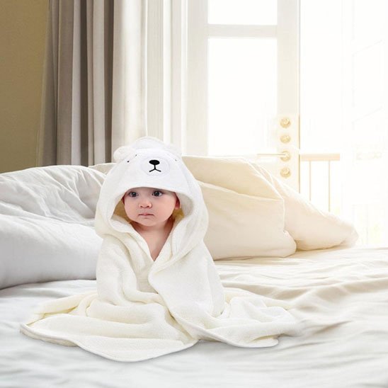 Cape de bain bébé bébé sur le sofa vêtu de sa cape de bain