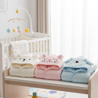 Cape de bain bébé trois couleurs disponible sur une table