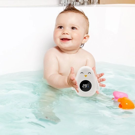 Thermomètre bain bébé bébé tenant son thermomètre assis dans son bain